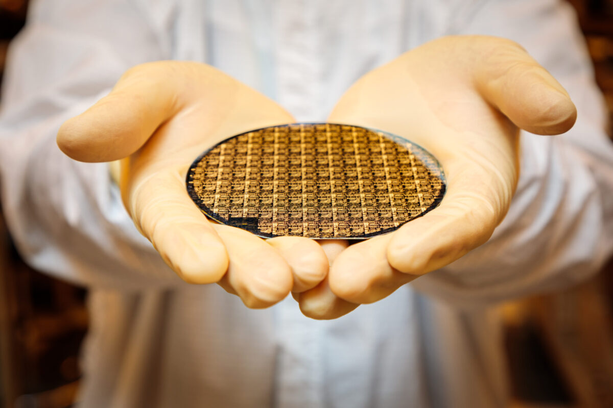 Two hands holding a semiconductor wafer.